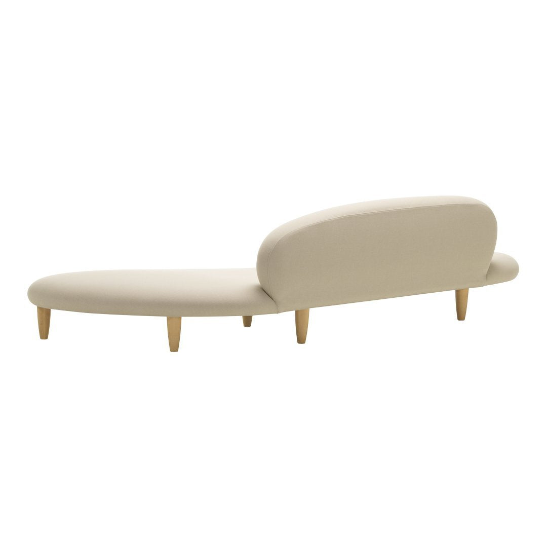 Minimalist beige chaise lounge with smooth contours and natural wood legs, perfect for modern decor.