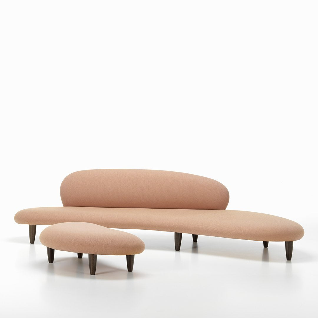 Curved pastel pink sofa set with smooth upholstery and dark wooden legs, featuring a minimalist design.