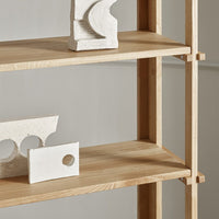 Light wood shelves with minimalist white decorative objects showcasing modern geometric patterns.