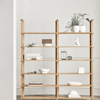 Natural wood shelving unit with neutral-colored decor and greenery, featuring clean lines and minimalistic design.
