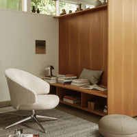 Cozy white textured chair against warm wooden backdrop, soft gray rug, and neutral decor elements in a serene setting.