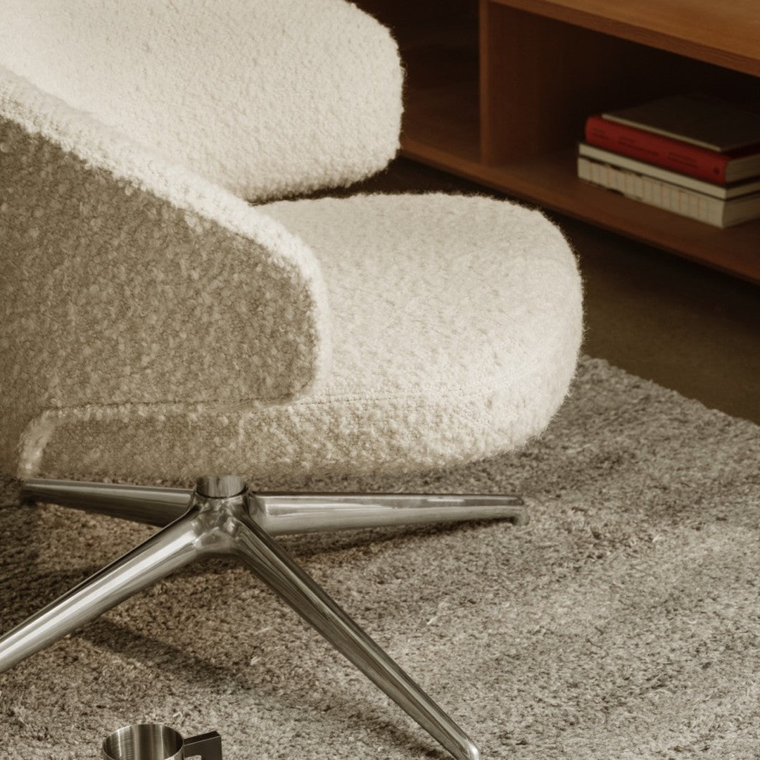 Cream textured chair with soft, fluffy upholstery and sleek silver legs on a grey rug. Modern, minimalist design.