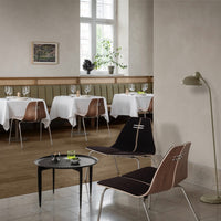 Elegant black and wood chairs on tiled floor, with green banquette and white tablecloths creating a modern dining atmosphere.