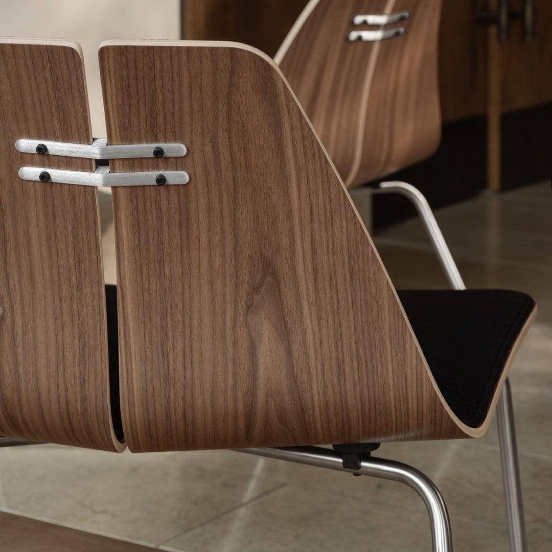 Wooden chair back in warm walnut tones with smooth silver accents and a black cushion, showcasing a modern design.