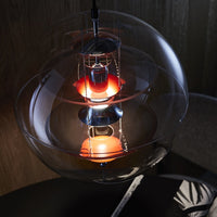 Circular pendant light with a clear glass shade and a striking orange and black design. Modern aesthetic, warm glow.