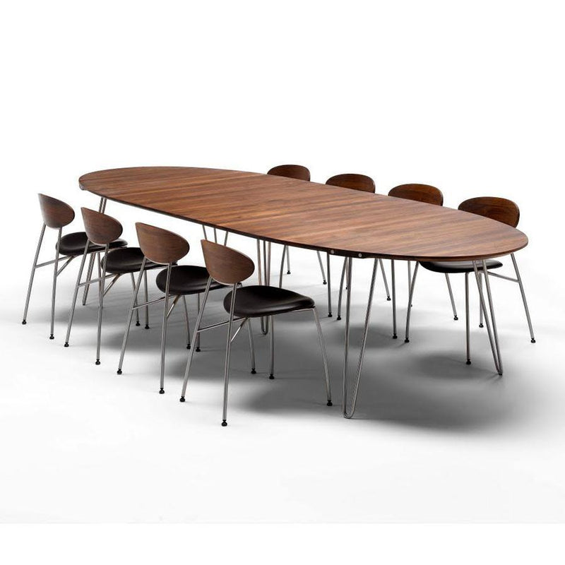 Wooden oval dining table with a rich brown finish and sleek black chairs featuring a modern design and chrome legs.