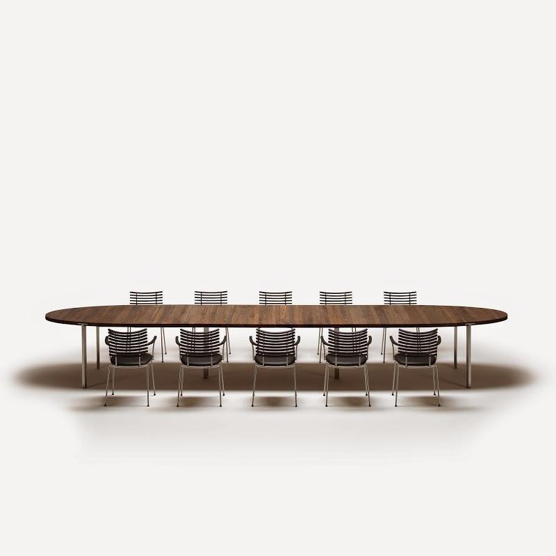 Elegant oval wooden dining table with a rich brown finish and six clear acrylic chairs, set on a minimalist white background.