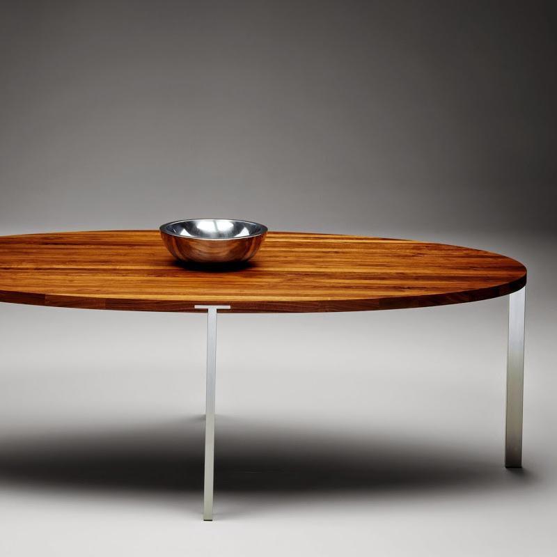 Sleek oval coffee table with rich brown wood grain and polished silver legs, minimalist design with modern elegance.