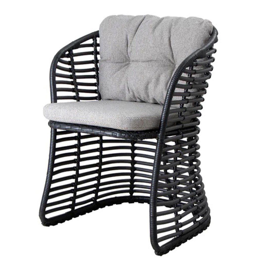 Black wicker chair with a textured gray cushion featuring a modern, curved design and open weave pattern.