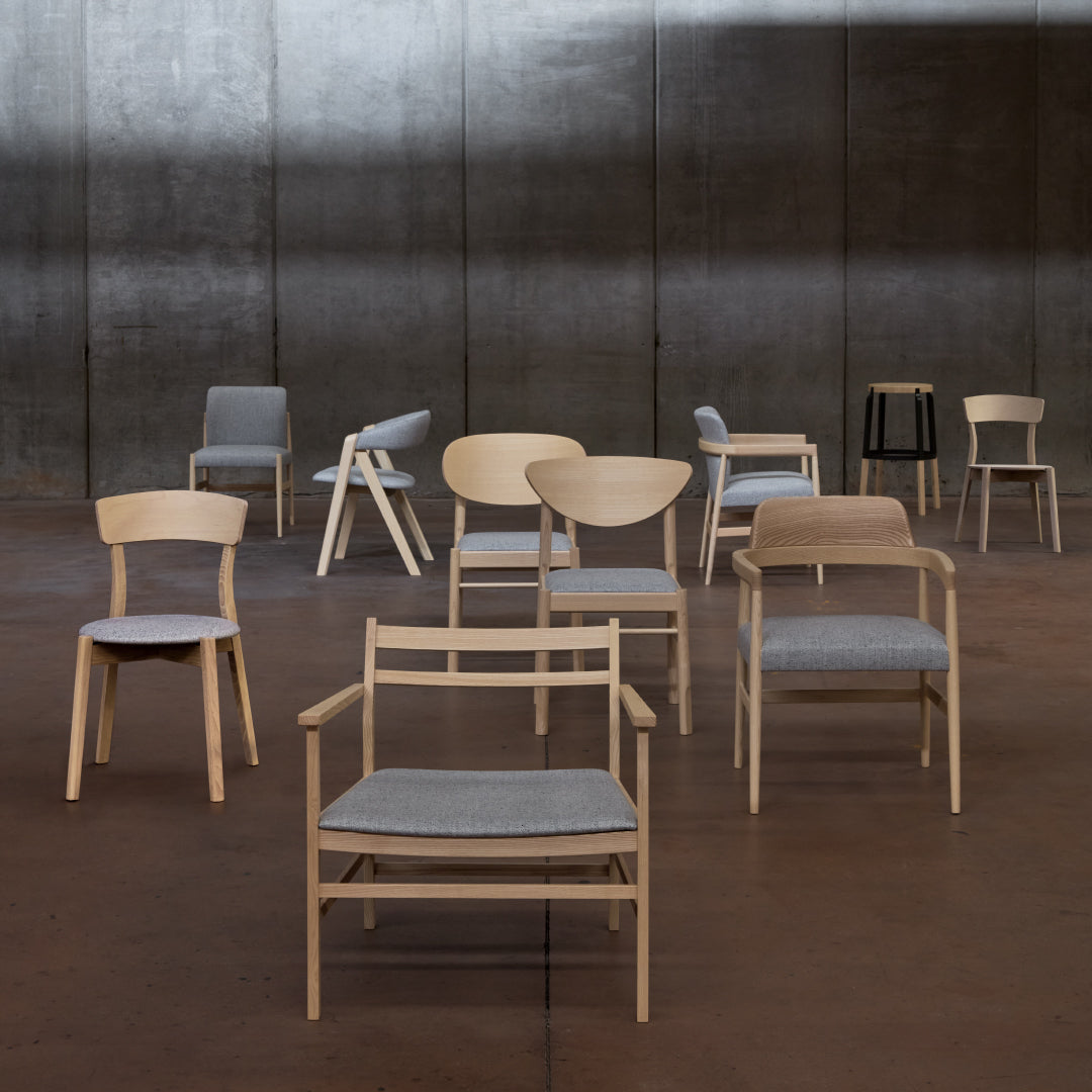 Assorted modern chairs featuring light wood tones and gray upholstery in a minimalist setting.