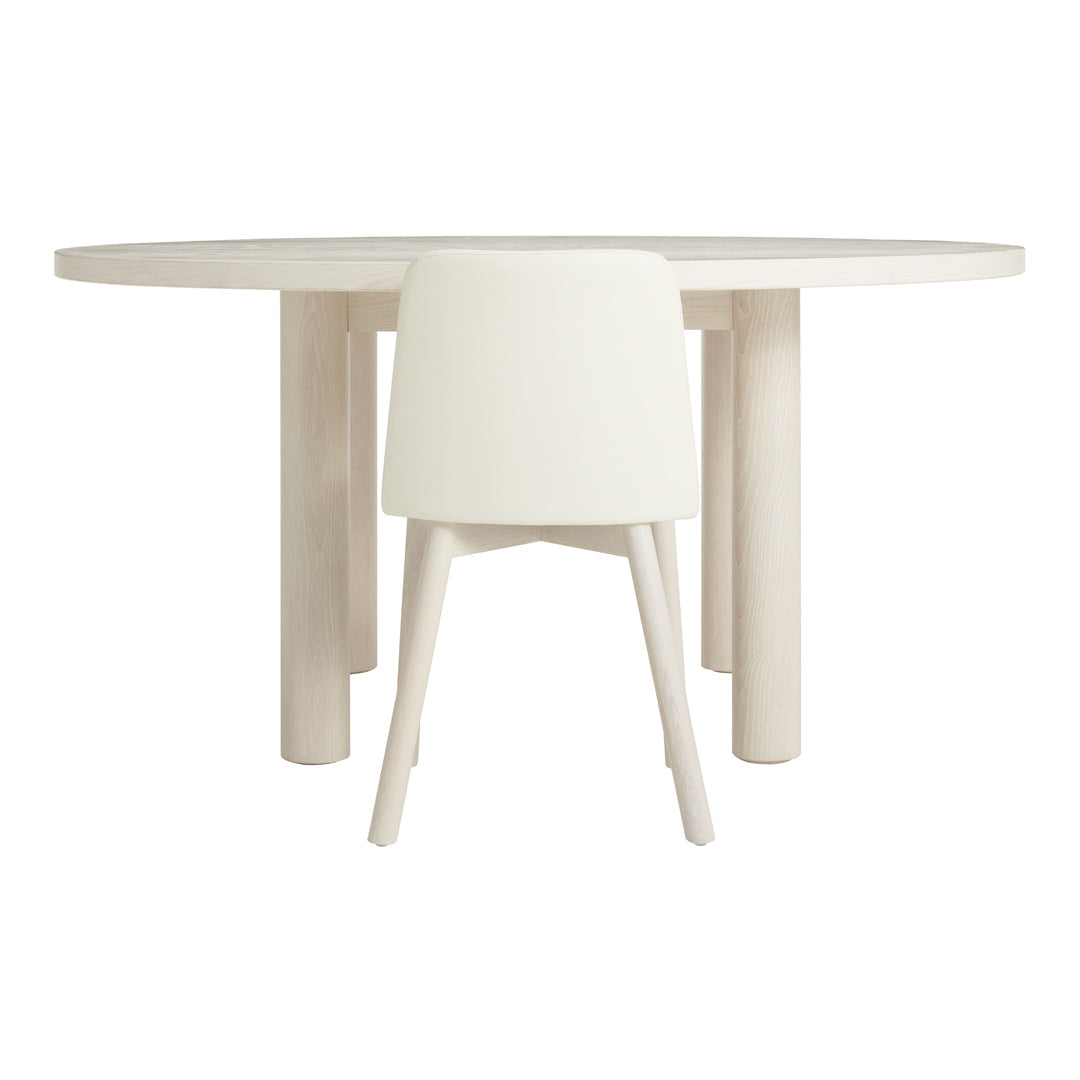 White round dining table with smooth, minimalist design and matching cream-colored chair. Modern, neutral aesthetic.