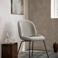 Light gray upholstered chair with a textured pattern, complemented by black metal legs against a neutral background.