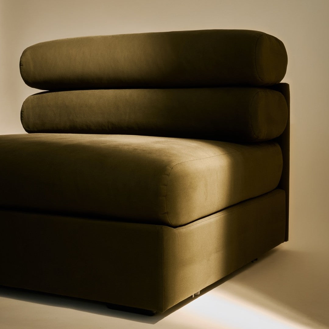 Dark green sofa with a smooth, minimalist design featuring layered, rounded cushions.