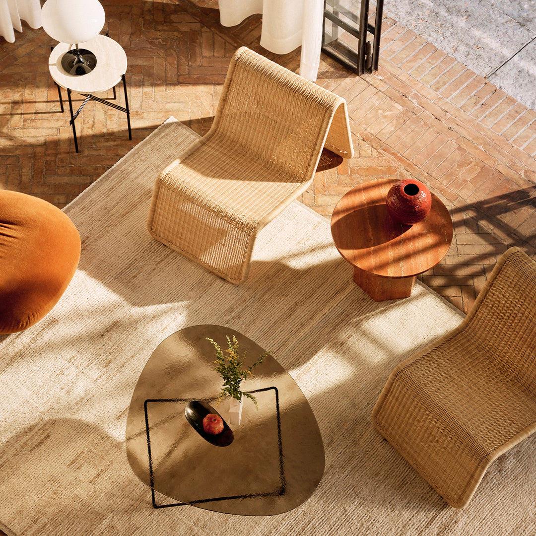 Natural beige wicker chairs on a textured light rug, paired with a round wooden side table and warm orange decor.