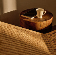 Natural woven pattern with soft beige tones, accented by warm wood and a simple white cup against a cozy backdrop.