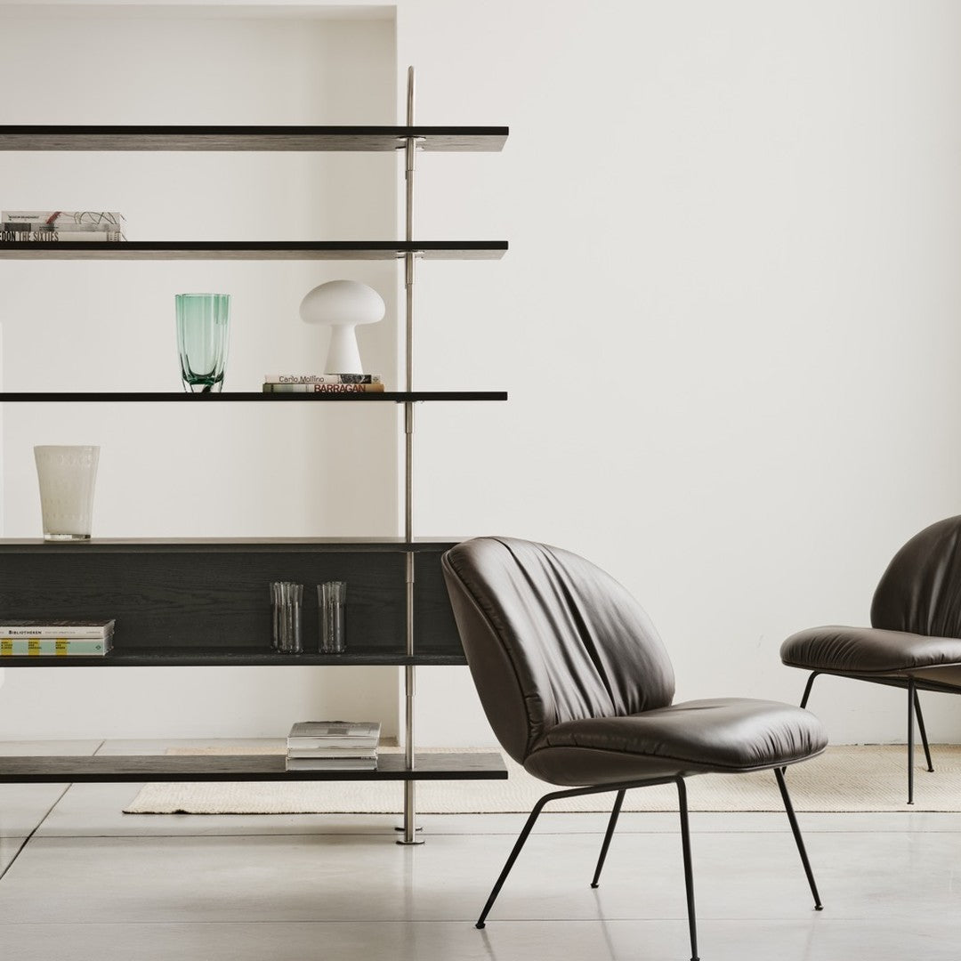 Brown leather chair against minimalistic black and white shelves, featuring glassware in green and clear tones.