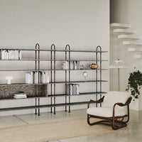 Modern shelving unit with black metal frame, neutral wooden shelves, and beige upholstery accents. Elegant minimalist design.