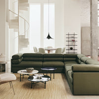 Olive green sectional sofa with black and white accent tables, neutral-toned decor in a bright, modern living space.