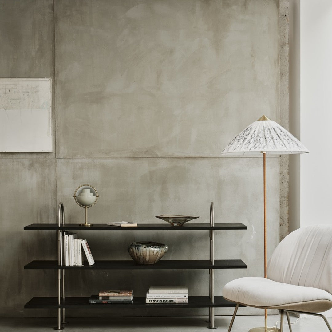 Minimalist black shelving against a textured gray wall, featuring a white patterned lamp and neutral decor elements.