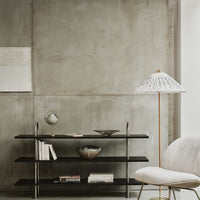 Minimalist black shelving against a textured gray wall, featuring a white patterned lamp and neutral decor elements.