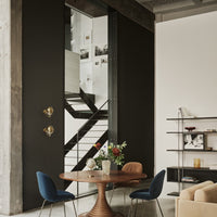 Modern interior with black walls, white accents, blue and tan chairs, and a wood table, featuring geometric patterns.