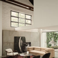 Modern living room featuring beige sofa, black and white artwork, and a red patterned rug against concrete walls.