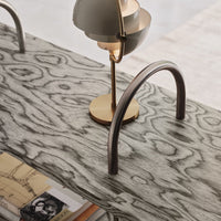 Gray wood texture with swirling patterns, accented by a gold lamp base and metallic silver arches.
