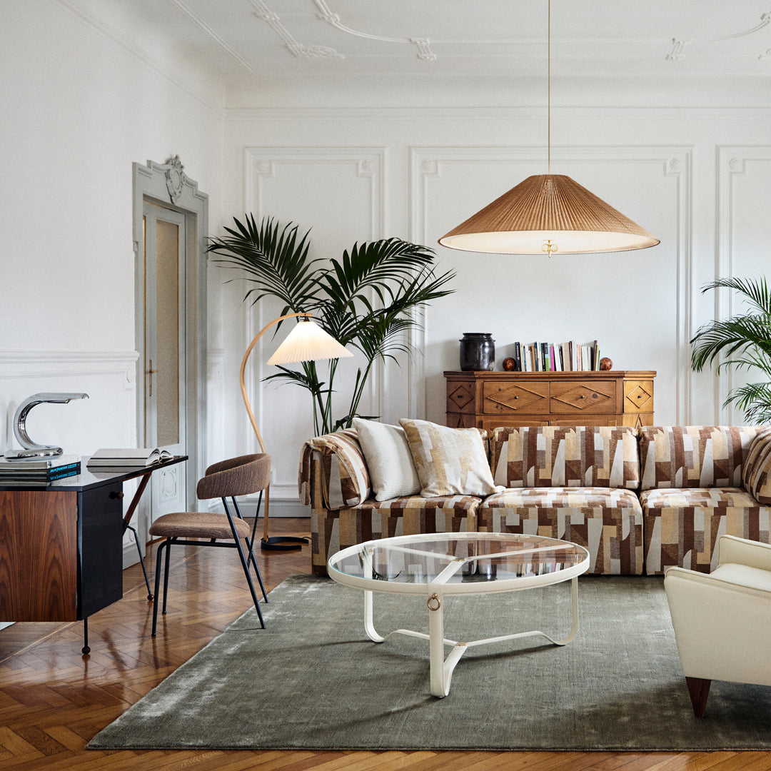 Striped beige and brown sofa with cream accents, complemented by a green rug and natural wood tones in the decor.