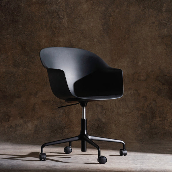 Black ergonomic chair on a dark textured background, featuring a sleek and minimal design with smooth, curved lines.