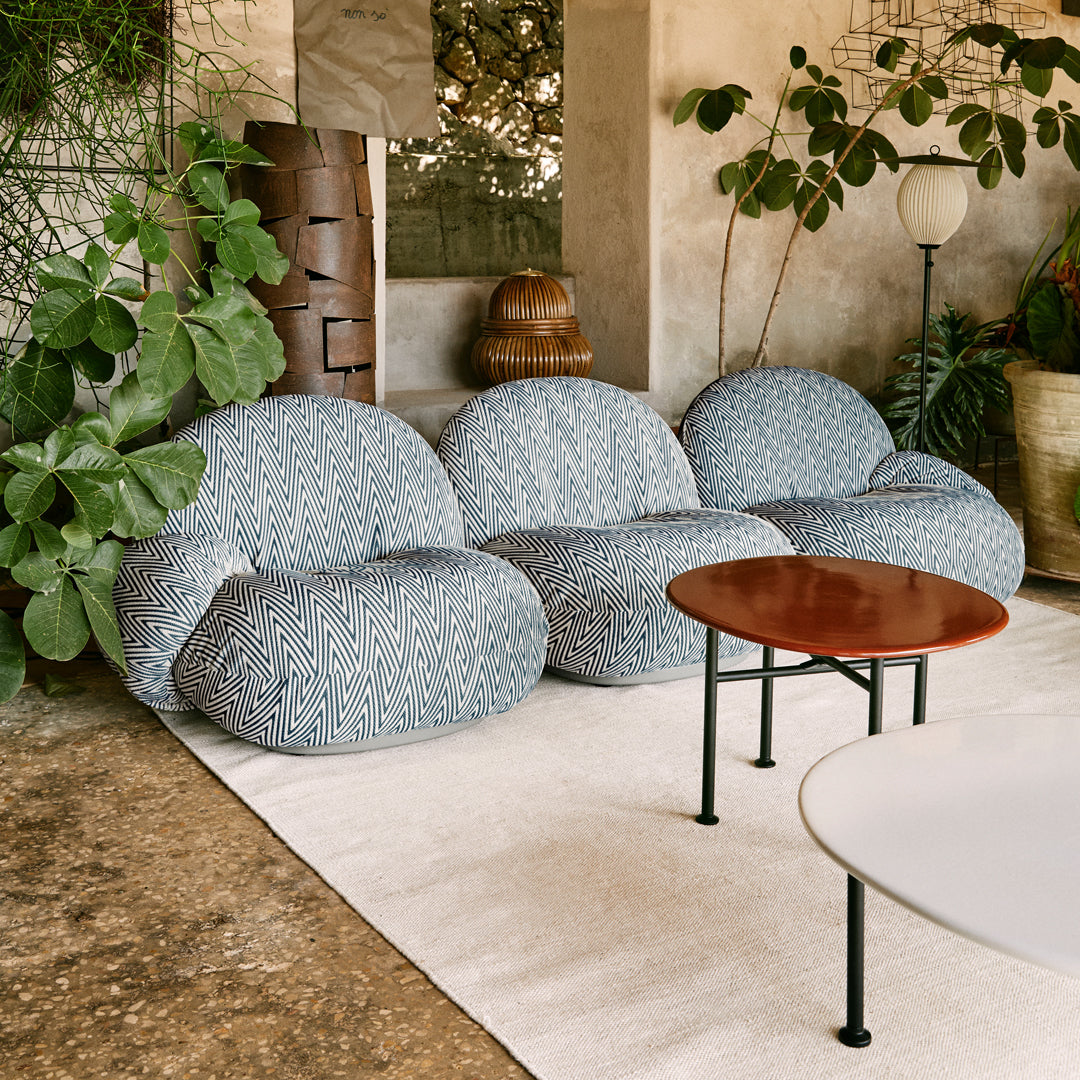 Blue patterned bean bag chairs with a textured design, set against a neutral background and greenery. Modern lounge setup.