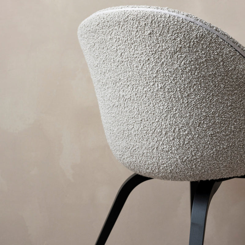 Textured light gray chair with a soft, fuzzy fabric and sleek black legs against a muted beige background.