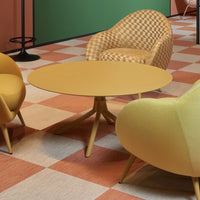 Yellow round table with textured surface, paired with orange and cream checkered chairs on a patterned floor.