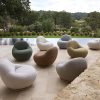 Colorful round lounge chairs in white, green, brown, yellow, and gray arranged outdoors by a serene pool area.