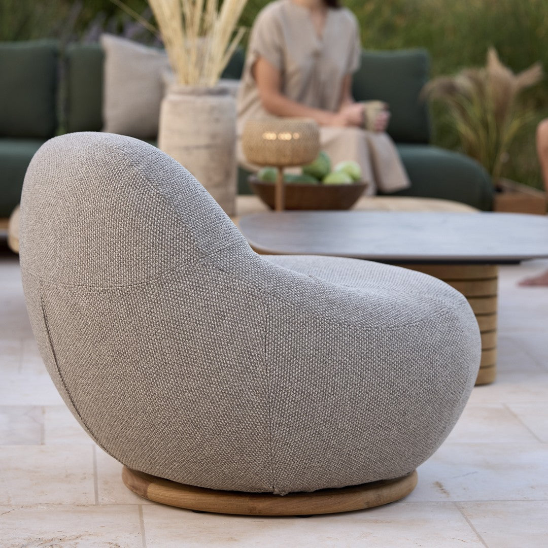 Stylish grey upholstered lounge chair with a rounded shape and natural wood base, perfect for modern outdoor settings.