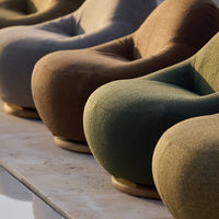 Curved chairs in earthy tones of brown, green, and gray with textured fabric and smooth wooden bases.