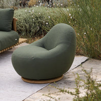 Curvy green lounge chair with soft texture, featuring a smooth, rounded shape and a natural wooden base.