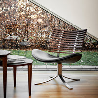Modern chair featuring a sleek black leather seat, striped wooden backrest, and a polished metal base. Natural light ambiance.