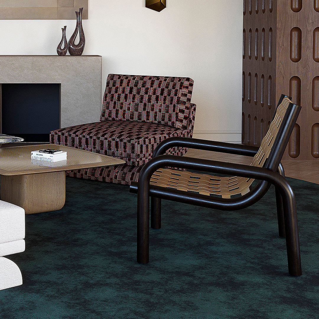 Stylish armchair featuring a patterned brown and beige seat against a dark green textured rug. Modern aesthetic.
