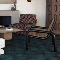 Stylish armchair featuring a patterned brown and beige seat against a dark green textured rug. Modern aesthetic.
