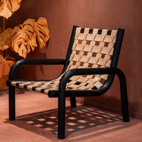 "Black and beige woven chair with a geometric lattice pattern, set against a warm, earthy backdrop."