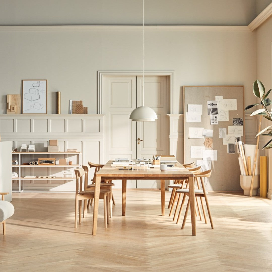 Modern dining room with light wood furniture, creamy walls, and a herringbone patterned floor in soft beige tones.