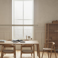 Light wood dining table with beige chairs; soft gray walls and natural light create a warm, minimalist atmosphere.