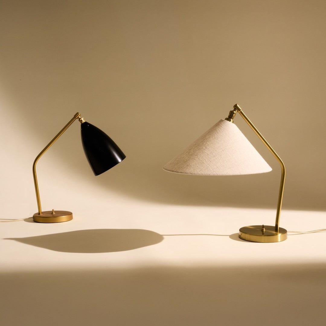 Black and beige table lamps with gold accents on a light backdrop, featuring sleek modern designs and contrasting textures.