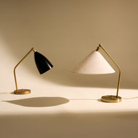 Black and beige table lamps with gold accents on a light backdrop, featuring sleek modern designs and contrasting textures.