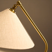 Cream linen lamp shade with a sleek gold metal arm, adding a touch of elegance to any decor.