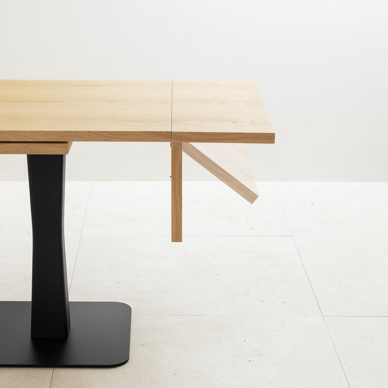 Light wooden table with a natural finish and sleek black base, featuring a clean, minimalist design.
