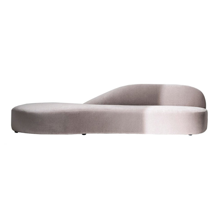 "Elegant curved chaise lounge in soft light gray velvet, featuring a smooth, modern silhouette."