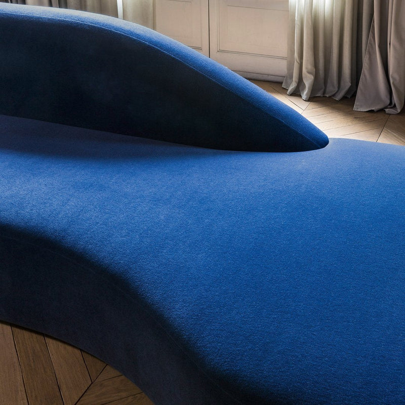 Vibrant blue curved sofa with a smooth texture, showcasing a modern and minimalist design.