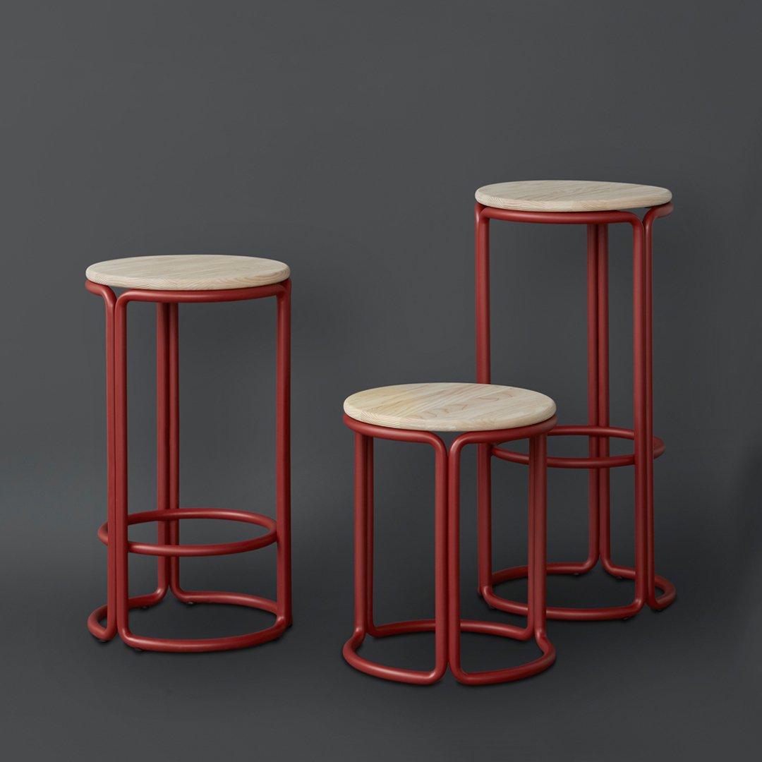Three modern stools with sleek red frames and light wood tops, showcasing a minimalist design against a dark background.