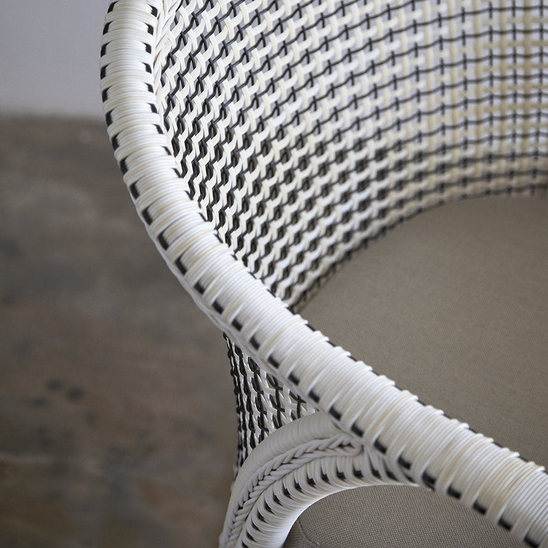 White woven chair with contrasting black and white patterns, featuring a smooth, neutral seat. Perfect for modern decor.